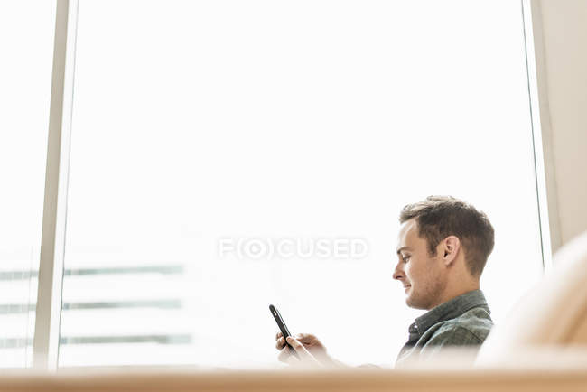 Uomo seduto in possesso di uno smartphone — Foto stock
