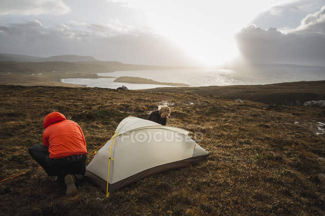 Homens segurando e montando uma pequena tenda — Fotografia de Stock