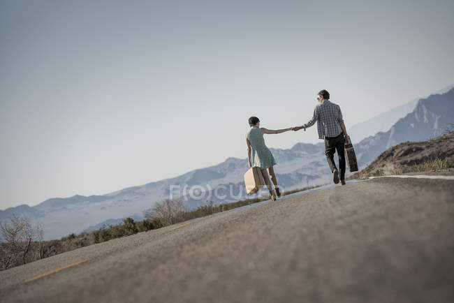 Casal em uma estrada de asfalto no deserto — Fotografia de Stock