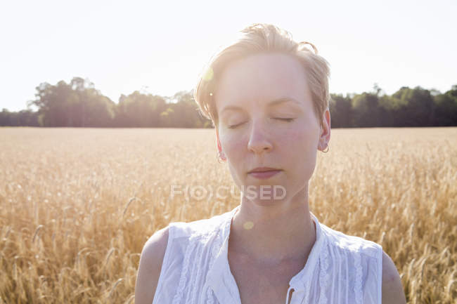 Young woman standing in a wheat field — Stock Photo