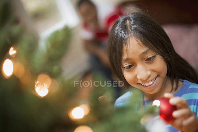Mädchen stellt Christbaumkugel auf Weihnachtsbaum — Stockfoto