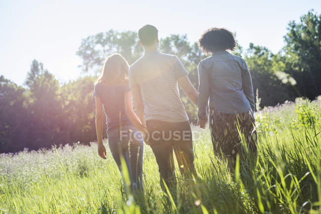 People walking hand in hand through grass — Stock Photo