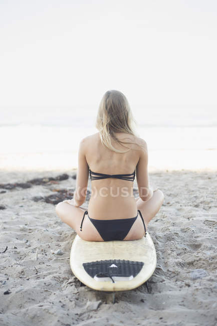 Femme blonde assise sur une planche de surf — Photo de stock