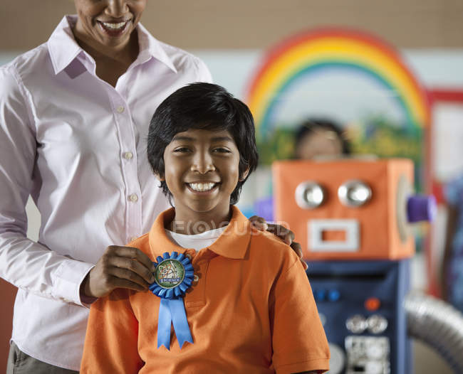 Woman awarding a rosette badge to a student — Stock Photo