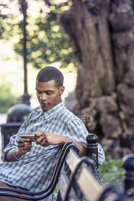 Мужчина с помощью смартфона на скамейке — стоковое фото