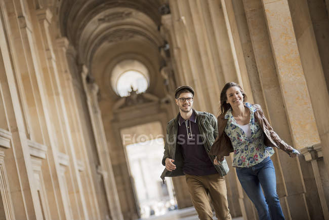 Couple walking down a colonnade — Stock Photo