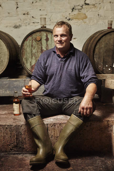 Man sitting among oak barrels — Stock Photo