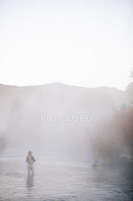 Fisherwoman flyfishing, standing in water. — Stock Photo