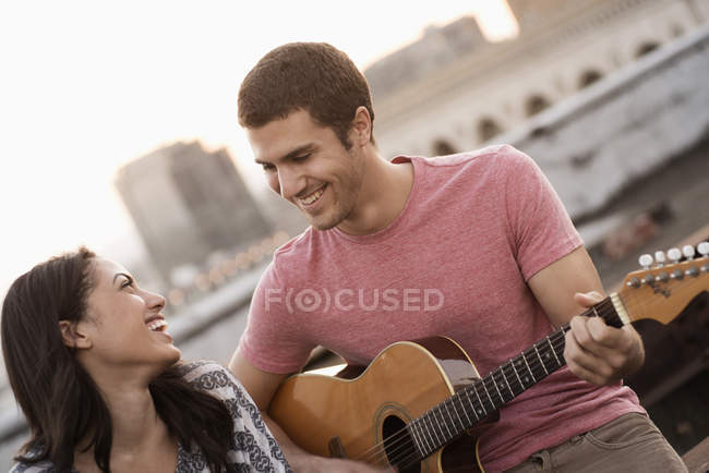 Homme jouant une guitare à une femme — Photo de stock