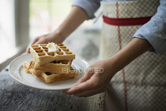 Woman holding a plate of waffles — Stock Photo