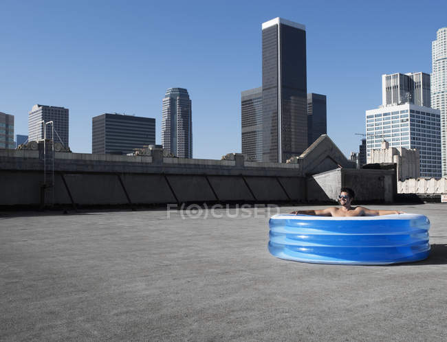 Man in inflatable pool on rooftop — Stock Photo