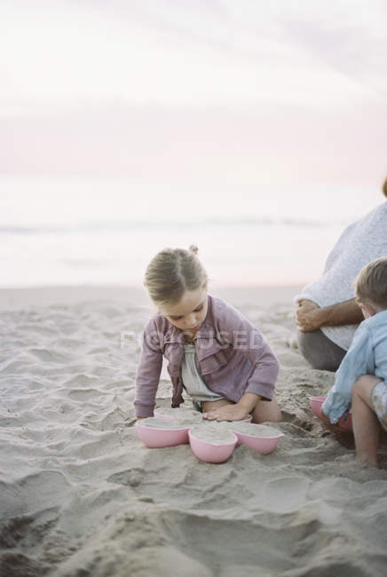 Niño y niña jugando en la arena - foto de stock