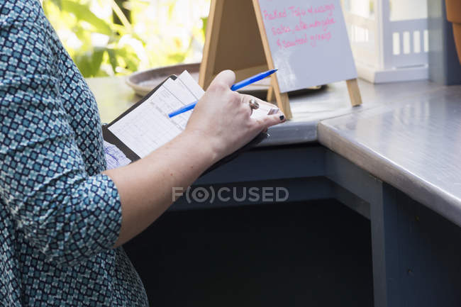 Pessoa em um café segurando uma conta e uma caneta — Fotografia de Stock