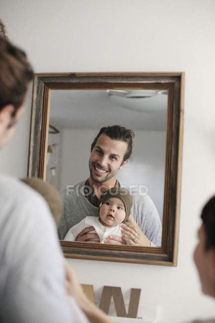 Parents avec leur bébé, regardant dans le miroir . — Photo de stock