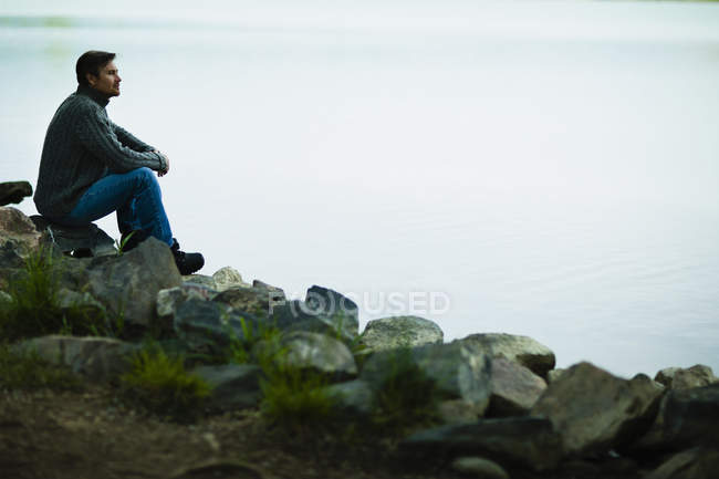 Мужчина среднего возраста, сидящий на камнях — стоковое фото