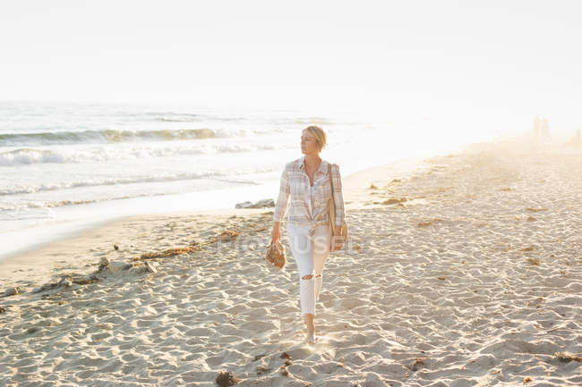 Женщина, идущая вдоль песчаного пляжа — стоковое фото