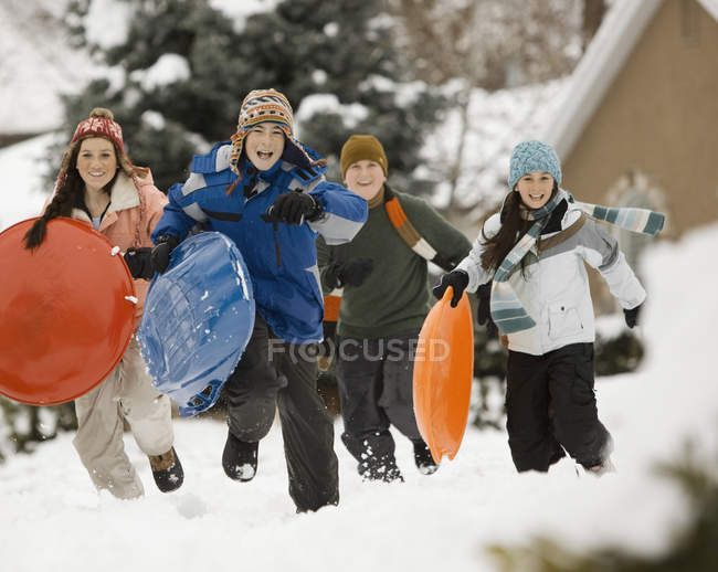 Діти бігають по снігу, несучи санки . — стокове фото