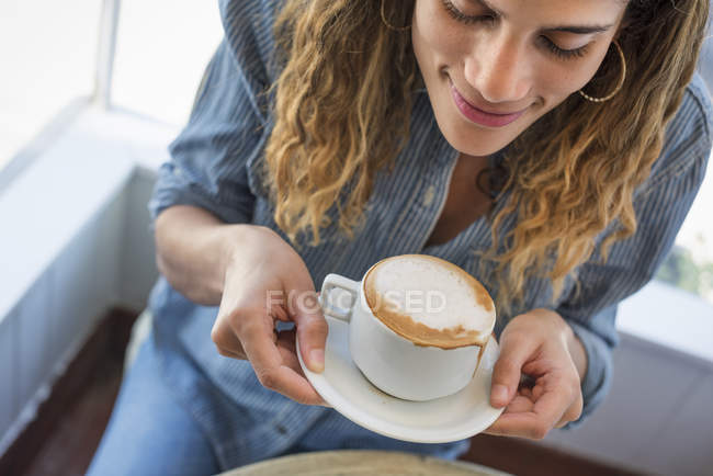 Mujer sosteniendo taza de acoffee en la cafetería - foto de stock