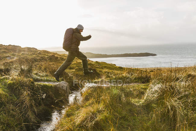 Mann springt über einen kleinen Bach — Stockfoto