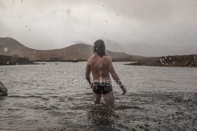 Homem de pé coxa profunda no mar — Fotografia de Stock