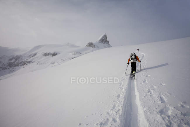 Esquiadores subindo um cume — Fotografia de Stock