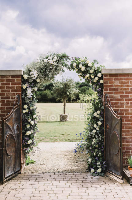 Arco de rosa blanca en un jardín - foto de stock