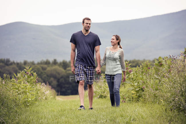 Hombre y mujer caminando a través de un prado - foto de stock