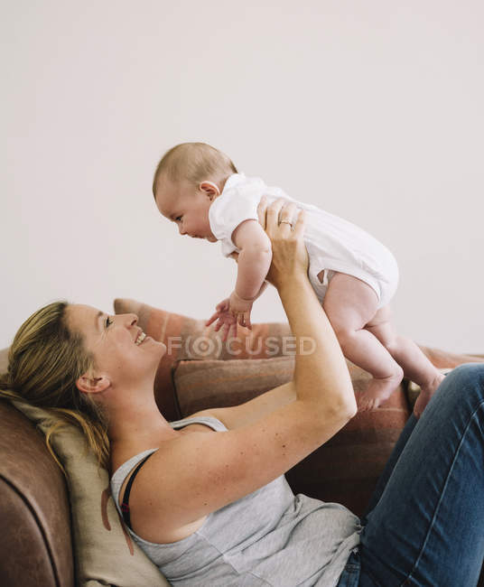 Frau liegt mit Baby auf Sofa. — Stockfoto