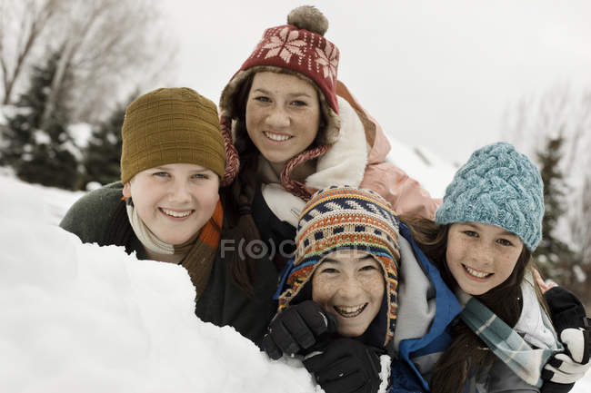 Children grouped laughing by a snow bank. — Stock Photo