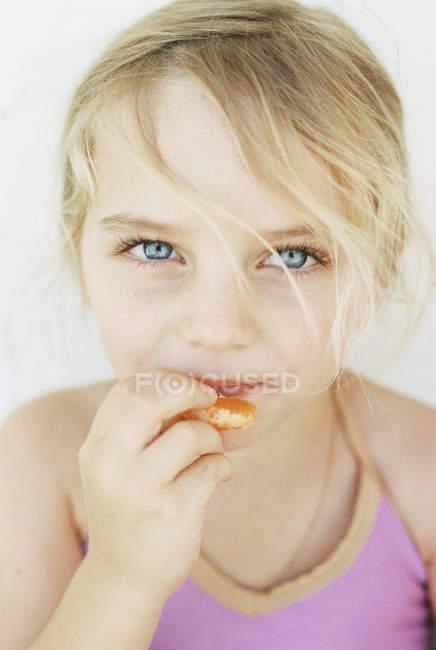 Menina loira comendo um mandarim — Fotografia de Stock