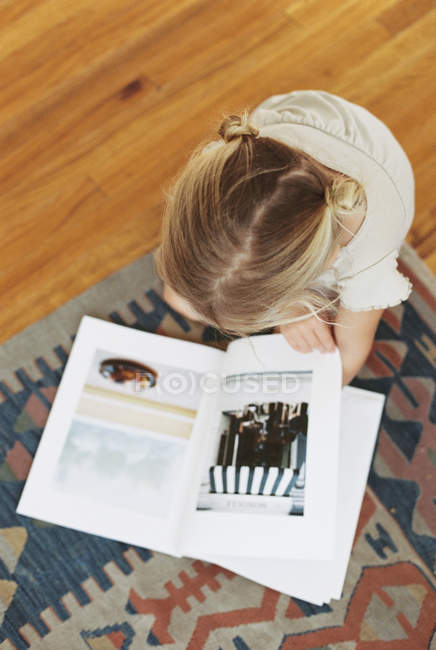 Jeune fille lisant un livre sur le sol — Photo de stock