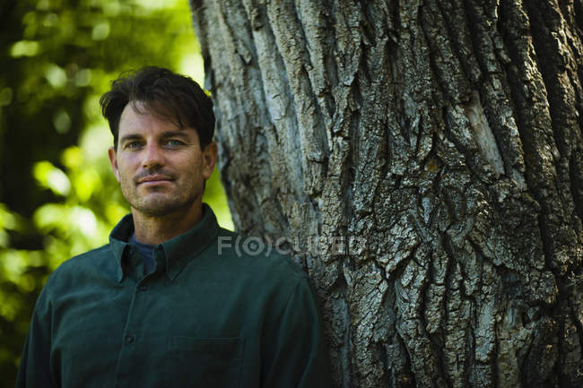 Homme debout près d'un grand arbre — Photo de stock