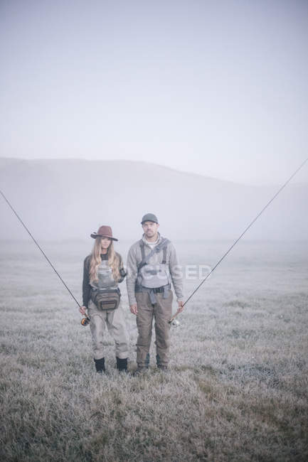 Personas en la niebla que llevan cañas de pescar . - foto de stock