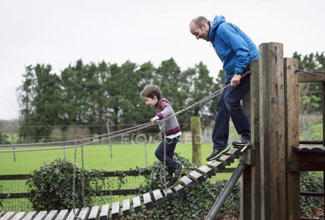 Niño y padre escalando en la pasarela - foto de stock