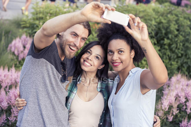 Les femmes et un homme posant pour un selfie — Photo de stock