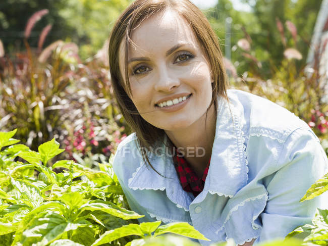 Mujer rodeada de plantas en un jardín - foto de stock