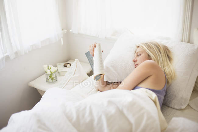 Mulher lendo em uma cama — Fotografia de Stock