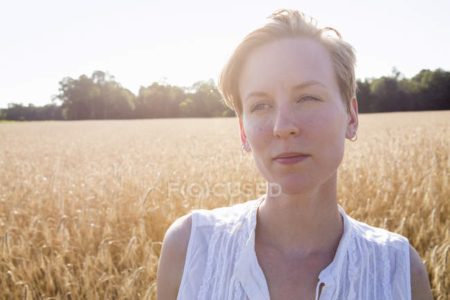 Молода жінка стоїть на пшеничному полі — стокове фото