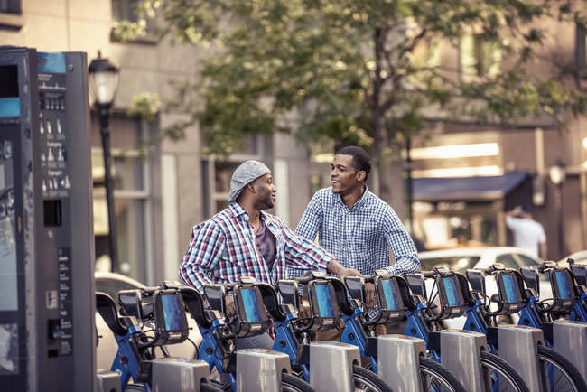 Men by a rack of bicycles for hire — Stock Photo