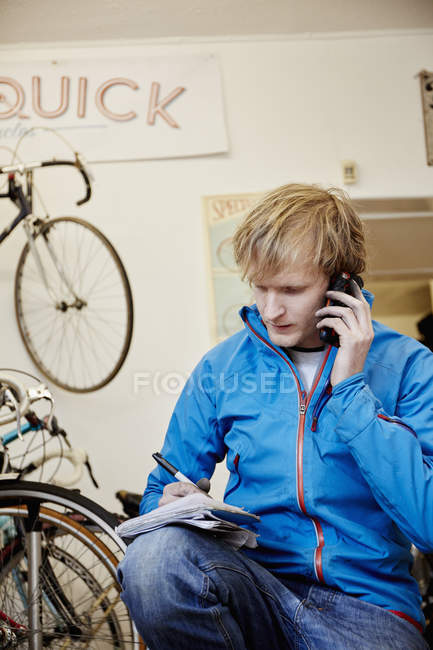 Hombre haciendo una llamada en la tienda de bicicletas - foto de stock