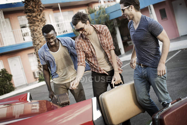 Amigos empacando el coche con maletas - foto de stock