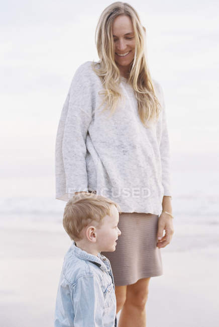 Mujer en la playa de arena con hijo - foto de stock