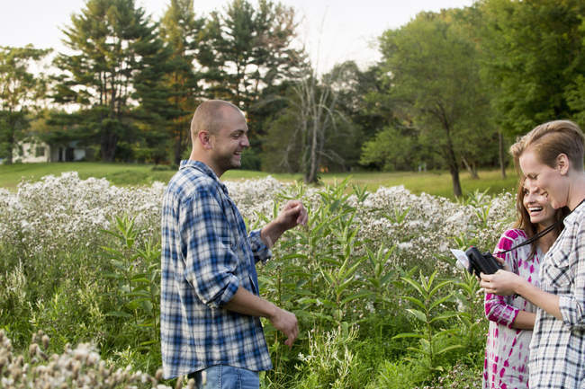 Homem e duas mulheres em pé em um prado de flores silvestres — Fotografia de Stock