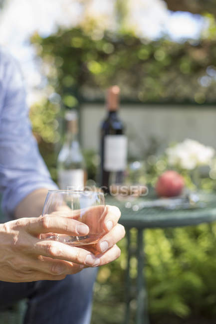 Uomo con in mano un bicchiere di vino rosato . — Foto stock
