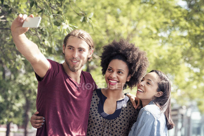 Man and women taking selfies in city park — Stock Photo