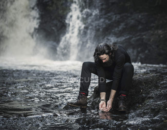 Man washing hands in a mountain stream. — Stock Photo