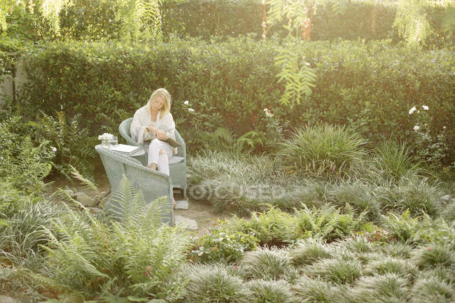 Frau sitzt im Garten und liest — Stockfoto