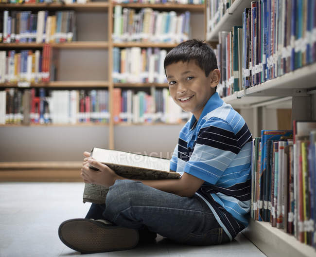 Junge liest in einer Bibliothek ein Buch. — Stockfoto