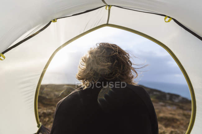Homem sentado no abrigo de uma tenda — Fotografia de Stock