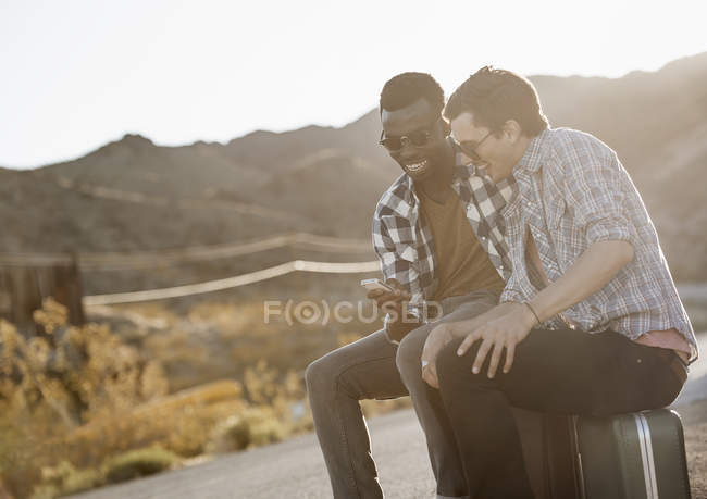 Men sitting by the roadside on their cases — Stock Photo